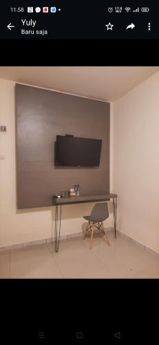 a room with a table and a tv on a wall at Zester Hotel Sidoarjo in Sidoarjo