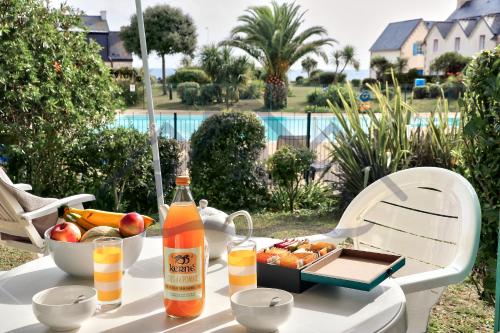 un tavolo con una bottiglia di alcol e un vassoio di frutta di LocaLise - A05 - Plain-pied avec petite vue mer donnant sur la piscine et le jardin - Wifi inclus - draps inclus - animaux bienvenus - parking gratuit a Le Guilvinec