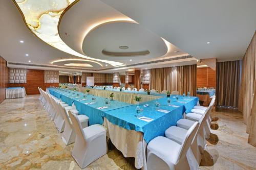 a large banquet hall with blue tables and white chairs at The Fern Residency Ajmer in Ajmer
