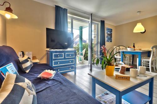 un soggiorno con divano blu e TV di LocaLise - A05 - Plain-pied avec petite vue mer donnant sur la piscine et le jardin - Wifi inclus - draps inclus - animaux bienvenus - parking gratuit a Le Guilvinec