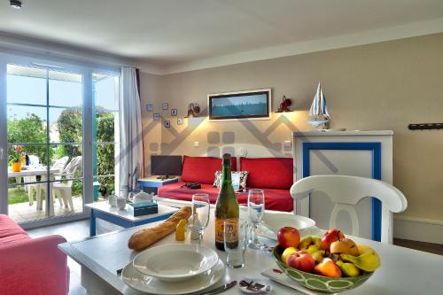 salon ze stołem i miską owoców w obiekcie LocaLise - A06 - Entièrement de plain-pied avec petite vue mer - Donnant sur la piscine et le jardin - wifi inclus - draps inclus - w mieście Guilvinec