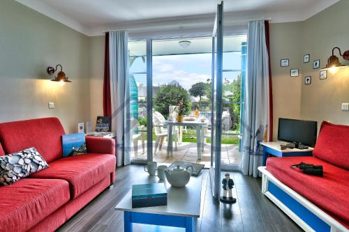 salon z czerwoną kanapą i telewizorem w obiekcie LocaLise - A06 - Entièrement de plain-pied avec petite vue mer - Donnant sur la piscine et le jardin - wifi inclus - draps inclus - w mieście Guilvinec