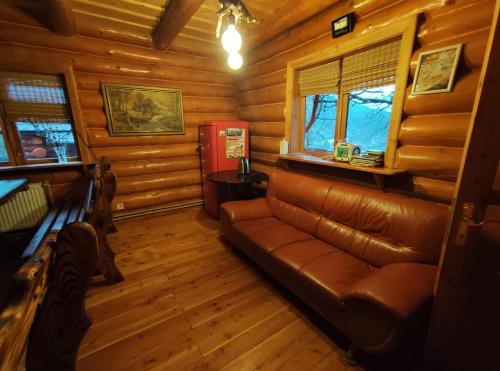 a living room with a leather couch in a log cabin at Дерев'яний котедж "Казка" in Yaremche