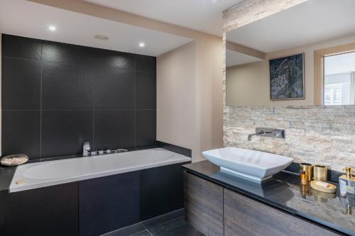 een badkamer met een wit bad en een wastafel bij Brussels Penthouse Prestige in Brussel