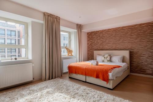 een slaapkamer met een bed met een oranje deken en een raam bij Brussels Penthouse Prestige in Brussel