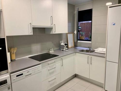 a kitchen with white cabinets and a sink and a window at PISO CENTRICO CON PATIO PRIVADO in Madrid