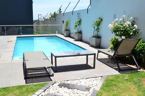 eine Terrasse mit einem Pool, 2 Stühlen und einem Tisch in der Unterkunft Soldout Camp 1 in Johannesburg