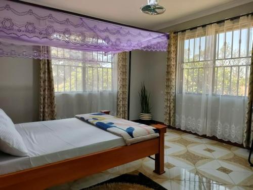 a bedroom with a canopy bed and windows at Keeney House at St. Gabriel's in Arusha