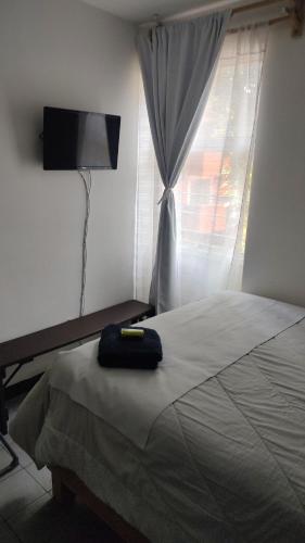 a bedroom with a bed and a window with a television at Cómoda y tranquila recámara cerca de Aeropuerto Benito J baño compartido in Mexico City