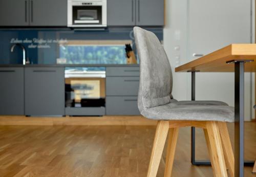 a gray chair sitting next to a table in a kitchen at Zapfig Living Arlberg in Wald am Arlberg