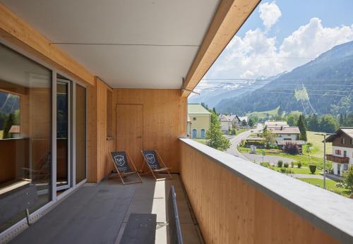 a balcony with two chairs and a view of a mountain at Zapfig Living Arlberg in Wald am Arlberg