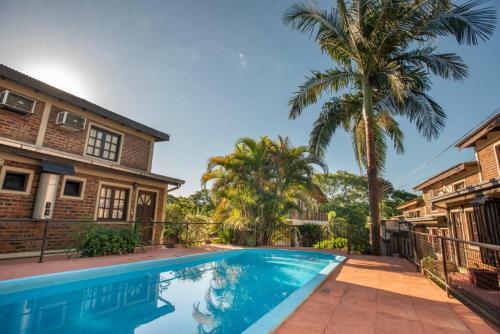 a swimming pool in front of a house with palm trees at LOS HELECHOS II in Puerto Iguazú