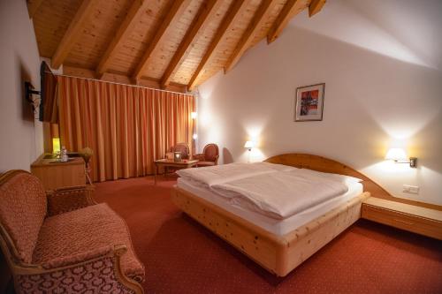 a bedroom with a bed and chairs in a room at Wellnesshotel Liun B&B in Müstair