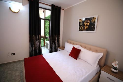 1 dormitorio con cama blanca y roja y ventana en Little Corner Hostel en Tirana