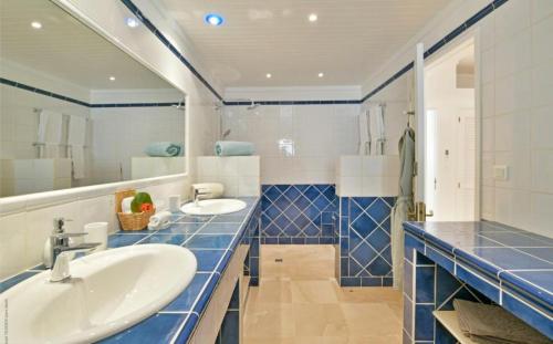 La salle de bains est pourvue de deux lavabos et de carreaux bleus. dans l'établissement Saint Barth Villa 1, à Saint-Jean