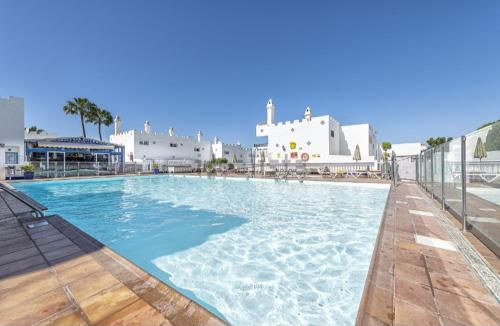 a large swimming pool in a resort with white buildings at Bungalow del sol in Playa del Ingles