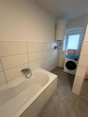 ein weißes Badezimmer mit einer Badewanne und einer Mikrowelle in der Unterkunft Appartement Niederthalheim 