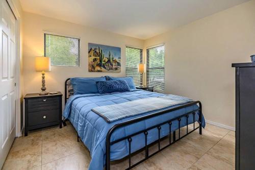 a bedroom with a bed with a blue comforter and two windows at Pools / Hot Tub / 3 Bedroom Condo / Ventana Canyon in Tucson