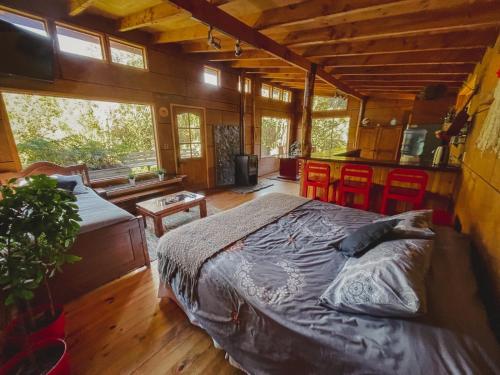 ein Schlafzimmer mit einem Bett in einem Haus mit Fenstern in der Unterkunft Cabañas Los Cantos del Chucao in Puerto Varas