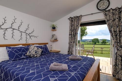 a bedroom with a blue bed and a sliding glass door at Ash Lodge - Exclusive Lodge with Hot Tub and stunning views in Bradpole