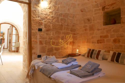 Habitación con toallas en una cama con pared de piedra. en Trulli Dimore - Trulli Bruco, en Monopoli