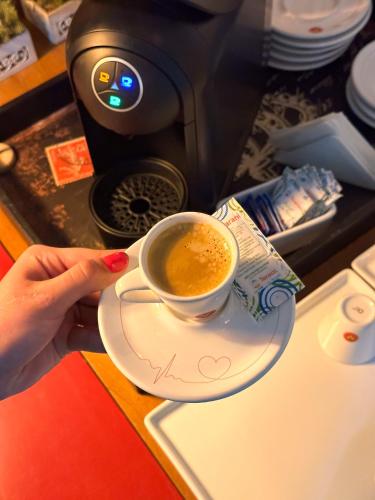 a person holding a cup of coffee on aucer at Cegil Hotel Boulevard in Resende