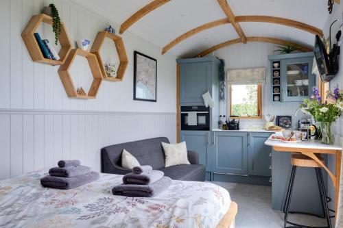 a living room with a bed and a kitchen at Honey Bee - Comfortable luxury shepherds hut with hot tub in Bradpole