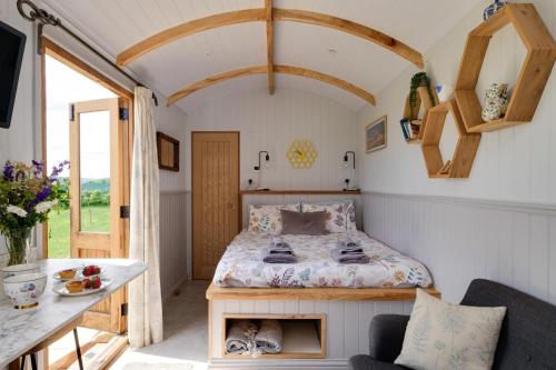 una piccola camera da letto con un letto e un tavolo di Honey Bee - Comfortable luxury shepherds hut with hot tub a Bradpole