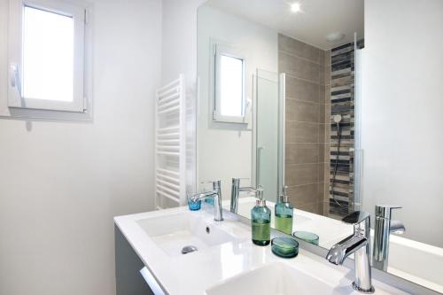 une salle de bain blanche avec un lavabo et un miroir dans l'établissement Chez Marie et Philippe - 1km de la plage, à Les Moitiers-dʼAllonne