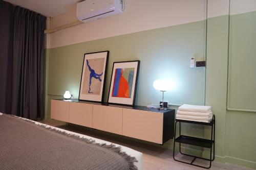 a bedroom with a bed and a dresser with paintings on the wall at Theme Stories - Boutique Guesthouse in Bangkok