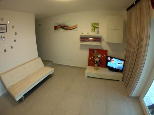 uma sala de estar com um sofá e uma televisão em Apartment Romana - next to the sea em Novalja