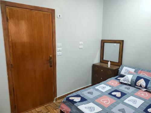 1 dormitorio con 1 cama con puerta de madera y espejo en Azazi house, en Quseir