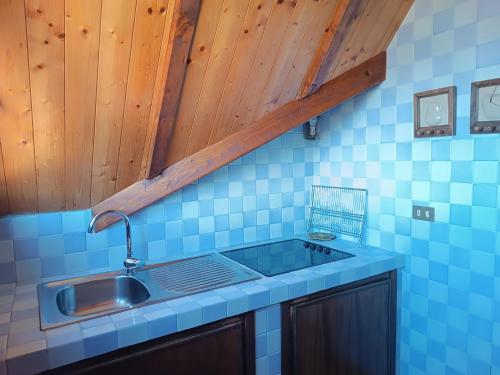 a kitchen with a sink and a blue tiled wall at Chiara Loft in Stresa