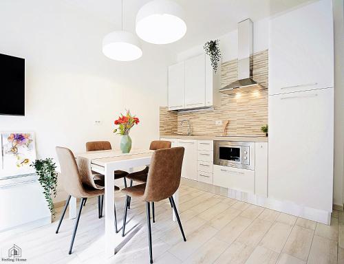 a white kitchen with a dining room table and chairs at Sweet Ap in Follonica
