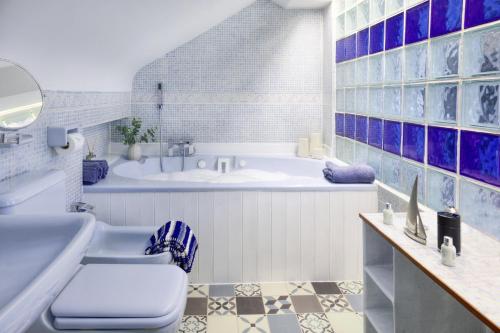 La salle de bains bleue et blanche est pourvue d'une baignoire et d'un lavabo. dans l'établissement Seaside spacious 4 BR Nr Town centre and Open Golf, à West Kirby