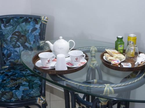 a glass table with a tea pot and cups and a chair at Hotel Serena in Naples