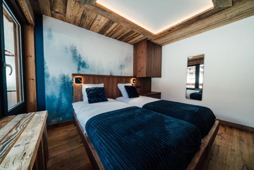 een slaapkamer met een groot bed en een blauwe deken bij Appartement Pixel by ExplorHome in Tignes