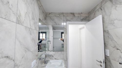 ein weißes Badezimmer mit einem Waschbecken und einem Spiegel in der Unterkunft Tango Departamento in Santa Teresita