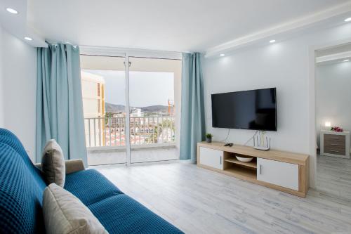 a living room with a blue couch and a television at Fantastic Apartment las americas heart in Arona