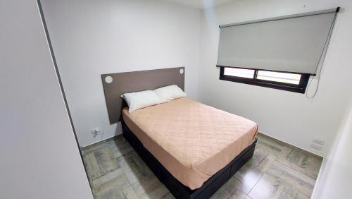a small bedroom with a bed and a window at Tango Departamento in Santa Teresita