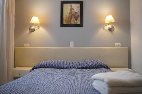 a bedroom with a bed and two lights on the wall at Hotel Crystal in Neuquén