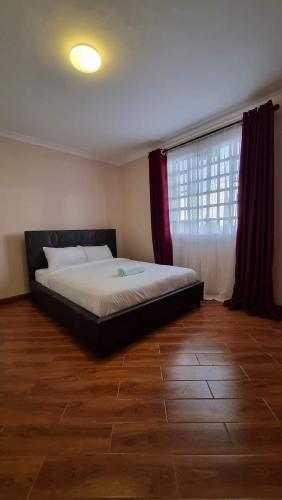 um quarto com uma cama num quarto com uma janela em C & T luxury apartments em Nakuru