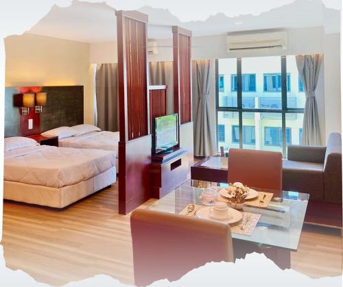 a hotel room with two beds and a table with a television at Studio Exclusive Swimming pool view by HERITAGE SUITES Near IMAGO Mall City Central , FREE HIGHSPEED WIFI & NETFLIX , KOTA KINABALU in Kota Kinabalu