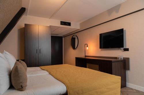 a hotel room with a bed and a flat screen tv at Grand Hotel Beatrix in Den Helder