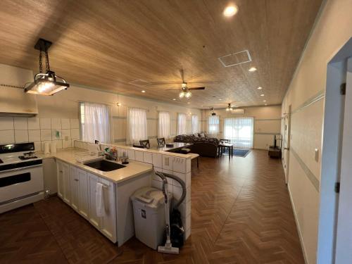 a kitchen with white cabinets and a living room at ペンション アラナハウス沖縄 in Toya