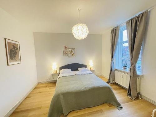 a bedroom with a bed and a window and a chandelier at aday - The Swanky Suite in Hjørring
