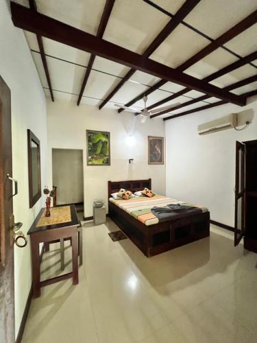 Sylvester Villa Hostel Negombo في نيجومبو: غرفة نوم فيها سرير وطاولة فيها