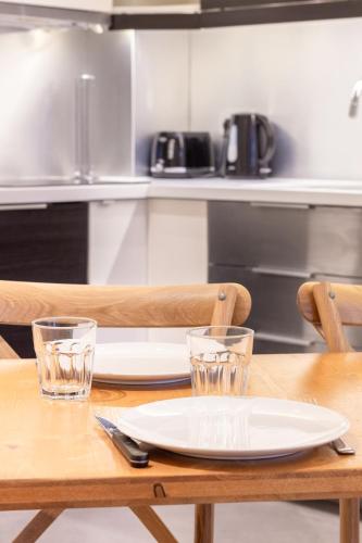 a wooden table with a plate and two glasses on it at Wonder Appart' 402 - Vue sur Garonne in Toulouse