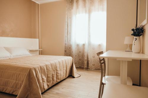 a bedroom with a bed and a table and a window at Affittacamere Mira Sinni in Episcopia