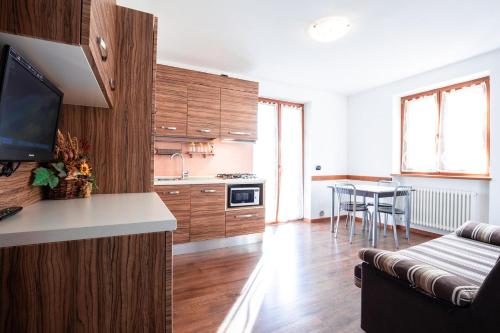 a kitchen with wooden cabinets and a living room at CROSINA HOLIDAY - Residence Toli in Ledro